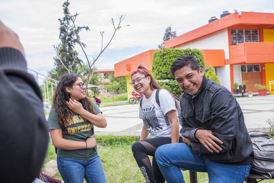 students laughing sitting outside of a campus building